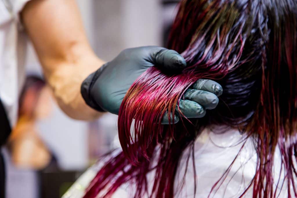 a hairdresser dyeing a customer’s hair multicolour with stretching colour dyed